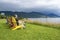 A Man Sitting in the First of a Row of Bright and Colorful Adirondack Chairs Facing the Ocean