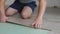 A man is sitting on the floor laying laminate. Master lay laminate on the floor in the room.