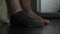 man sitting at home next to bed puts on gray socks on his dirty feet and is going to work in morning. Close-up of legs