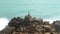 Man sitting on a huge boulder on a beach and looking at the sea