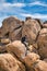 Man sitting on huge rocks against cloudy blue sky at Joshua Tree National Park