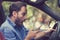 Man sitting inside car with mobile phone texting while driving