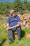 Man sitting on a log getting ready to chop pile of firewoods for winter kindling