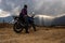 Man sitting at motorcycle at mountain top with dramatic sky at evening