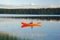 Man sitting in a red canoe on a lake in Finland at sunset