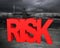 Man sitting on red risk word facing dark storm ocean