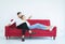 Man sitting on red sofa with woman and hand pointing out the window in living room at house,Happy and smiling,Positive attitude em