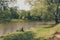 Man sitting on river bank is fishing among lush park greenery