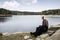 Man Sitting On Rock While Enjoying Lake View