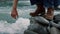 Man sitting on rock at stream. Male hand touching fresh water from river flow