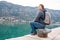 Man sitting on seat on harbor close to beautiful turquoise sea view and mountain