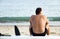 Man sitting on surfboard at beach.