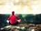 Man sitting on the top of the mountain in yoga pose. Exercise yoga on the edge with a breathtaking view