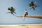 Man sitting on trunk of palm tree on idyllic beach