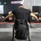 Man Sitting in a Wheelchair with a Backpack attached doing Arm and Shoulder exercises with Gym Equipment