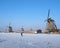 man skates on the ice near kinderdijk windmill in holland on sunny winter day