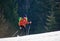 Man with ski mountaineering climb towards the summit under the lights of a sun against forest background