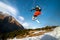 Man skier in flight after jumping from a kicker in the spring against the backdrop of mountains and blue sky. Close-up