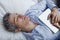 Man sleeping on bed with holding a digital tablet