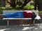 Man is sleeping on the bench of a park of Bologna, Italy