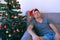 Man is sleeping sitting on couch at home near Christmas tree at eve, hangover.