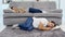 A man sleeps on the floor while his wife watches a TV