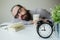 Man sleeps in office on table over laptop with coffee in hand