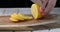 A man slices a lemon into slices on a wooden background. 4k video