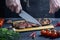 A man slices a steak with a knife and fork. Cropped photo with hands closeup. Fresh medium beef steak