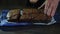 Man slicing cake on wooden table. Prepared chocolate cake pieces on kitchen