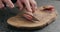 Man slicing fuet sausage on olive wood board