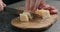 Man slicing parmesan hard cheese on olive wood board