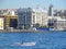 Man in small boat passing city buildings