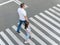 A man and a small child on a zebra crossing trespassing by crossing the street. In the summer on the street