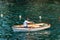 A man on a small wooden rowboat in the green sea - Liguria Italy