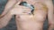 Man smearing cream on incomplete tattoo on his chest. Close-up of men`s hand applying ointment to part of body.