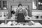 Man smile in chef hat in kitchen. Happy cook at table. Vegetables and tools ready for cooking dishes. Food preparation