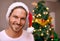 Man, smile and hat for Christmas, portrait and house with bokeh on tree for festive celebration in holiday for season