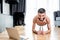 Man smiling at camera while standing in plank near laptop on floor at home