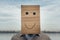 Man with a smiling cardboard face on the background of clouds