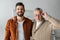 Man smiling while standing with cheerful senior father touching glasses