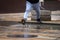 Man in sneakers and sweatpants jumps over a city puddle