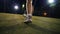 Man in sneakers walks to the ball and puts his foot on the ball, night shooting on the football field