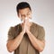 Man sneezing, blowing nose and tissue with virus and health issue against a grey studio background. Male person, guy and