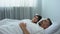 Man snoring in bed, annoyed wife waking up and pushing husband, health problem