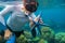 Man snorkeling in blue water with starfish. Snorkeling in coral reef. Snorkel holds blue starfish.