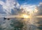 Man snorkeling in ocean with beautiful sunset in background, clouds and sun reflecting into water