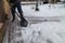 Man in snow boots cleaning snow on walkway in garden. Shoveling snow.