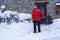 Man with snow shovel cleans sidewalks in winter near house. Winter time, snowfall. France Europe