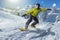 Man on a snowboard rides downhill in a wintry landscape with powdersnow